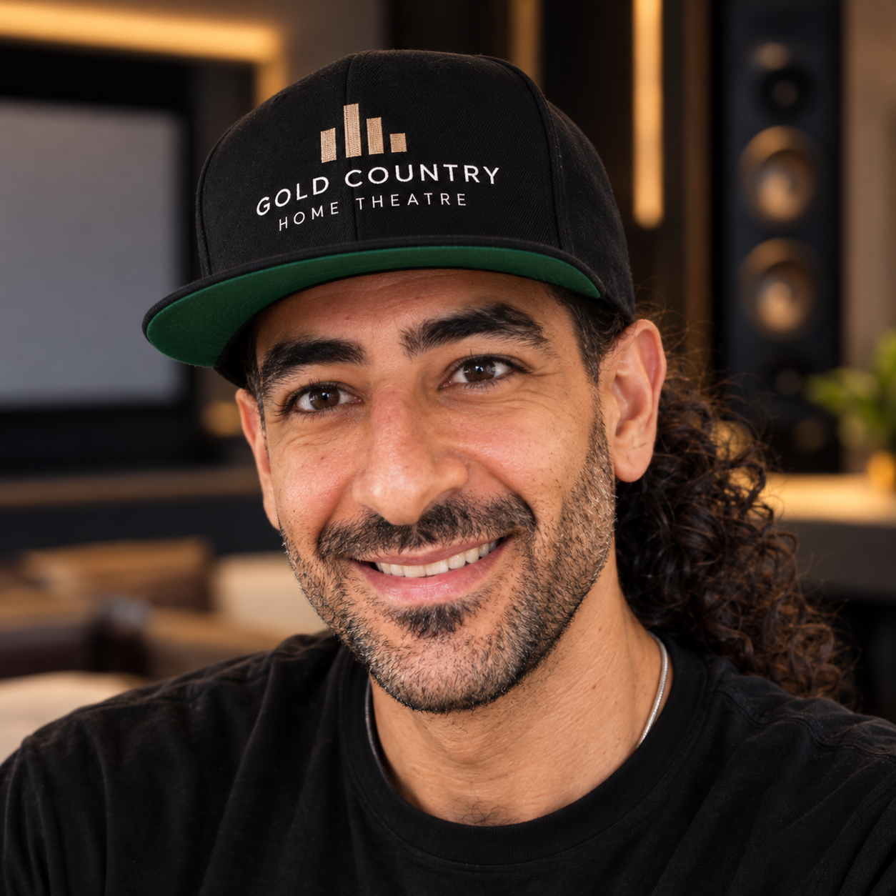 Shareef Mousa, founder of Gold Country Home Theatre, wearing a company cap in a home theater